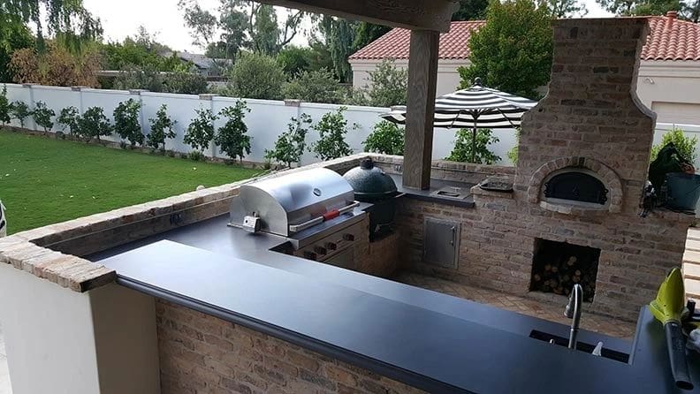 A grill and an outdoor kitchen with a brick wall