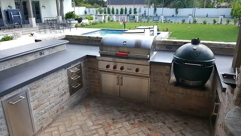 A grill and an outdoor sink in the middle of a patio.